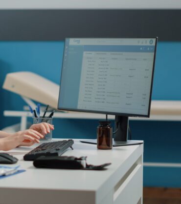 Nurse typing on computer keyboard for consultation and appointment. Medical assistant using technology for healthcare system in doctors office. Specialist working with medical equipment